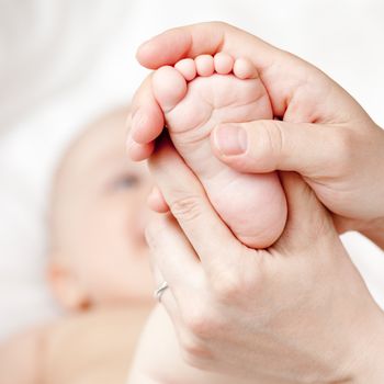 Masseur massaging her child's foot, shallow focus