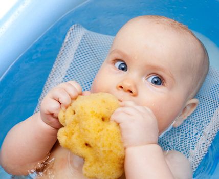 Little baby girl bathing with natural sponge