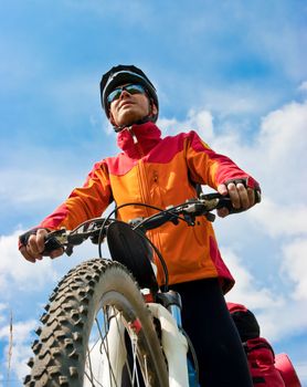 Portrait of adult cyclist on mountain bike against blue sky