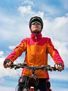 Portrait of adult cyclist on mountain bike against blue sky