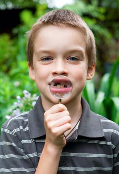 Young boy showing deciduous tooth thru hand magnifier