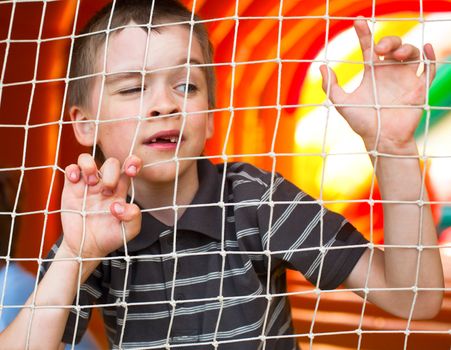 Young boy behind the net at playground