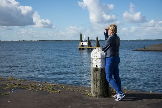 blue dressed woman thinking and staring at sea to the boats