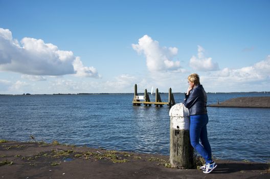 blue dressed woman thinking and looking at sea to the boats