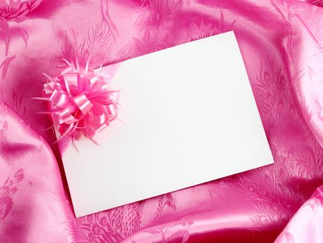 Blank gift card with ribbon on pink satin