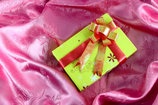 yellow gift box with ribbon on pink satin