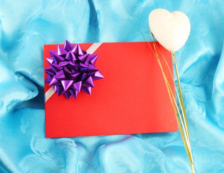 red gift card with ribbon on blue satin