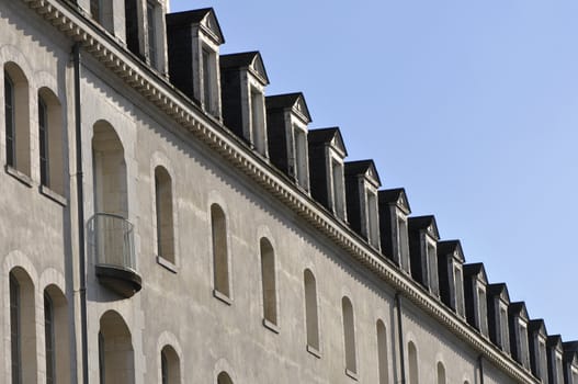 Many little windows on the roof of a building with a blue sky