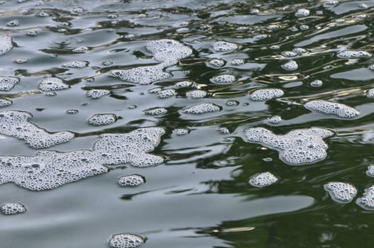 White Foam on the surface of green water with little waves