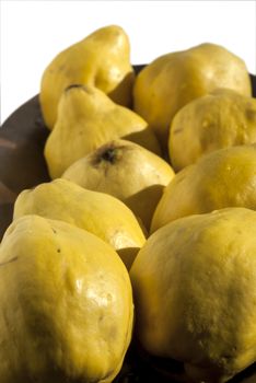 Organic quinces in wooden bowl isolated on white