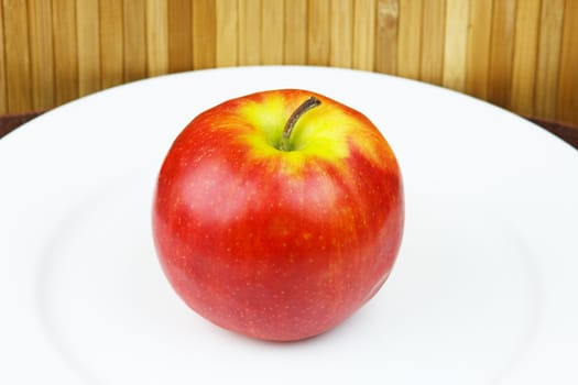 apple on a plate standing on a bamboo napkin