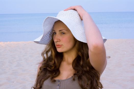 Portrait of woman wearing a hat from the sun on a blue background of the sea