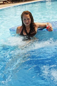 Girl with a cocktail in the pool