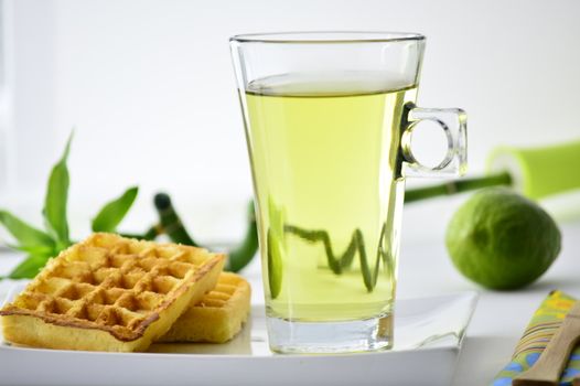 cup of tea and waffles on a plate in front of a lime and bamboo