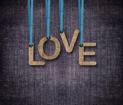 Love word hunging by rope as puppeteer on sackcloth background.