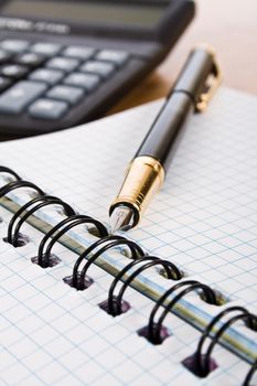 Calculator pen and notebook on white background