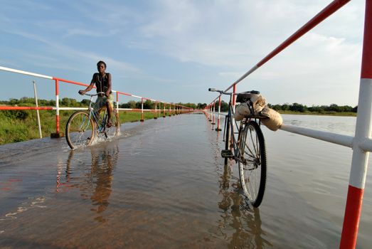 Ouagadougou,Burkina Faso October 2,2010: a woman in bicycle crosses a flooded road. In Ouagadougou the season of the rains provokes serious floods