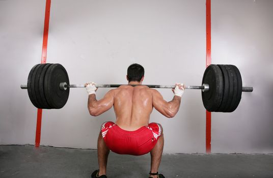 The concept of power and determination of a man lifting a weight bar. Back squat crossfit exercise. Focus on the back.