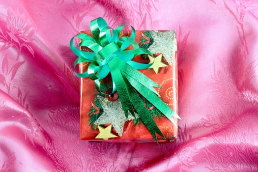 red gift box with green ribbon on pink satin