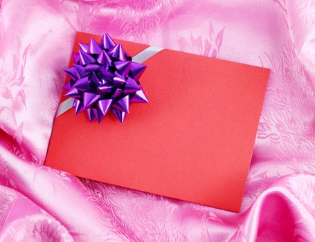 red blank gift card with ribbon on pink satin