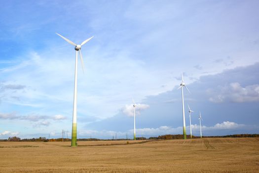 Many wind turbines, green grass and blue sky with the clouds. Go green!