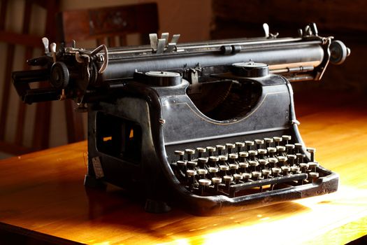 Old black dusty vintage typewriter on the table.