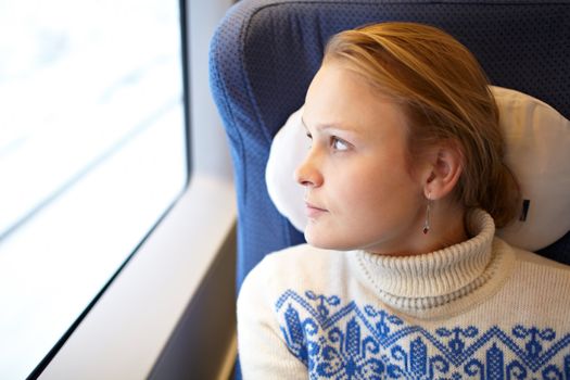 Young woman is watching window scenes and thinking in the modern high speed train.