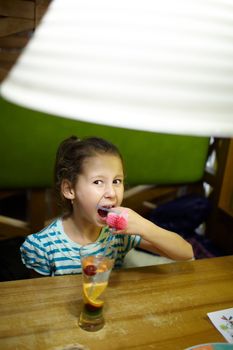 Eight year old girl is drinking coctail in the restaurant.