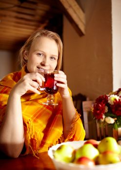 Young beautiful woman with birthmark on her face is drinking carcade tea and smiling at the wooden vintage style restaurant.