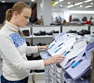 Young woman is choosing a shirt for her boyfriend.