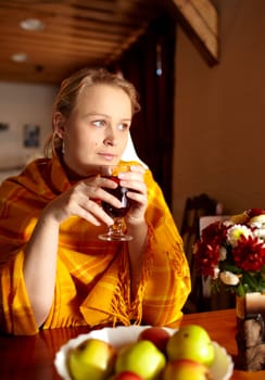 Young beautiful woman is drinking carcade tea and looking through the window.