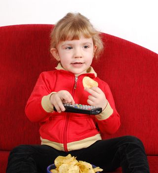 Little girl watching tv and eating chips