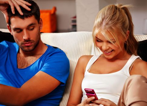 bright picture of couple at home with cellphone (focus on woman)