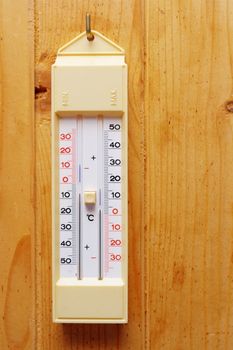 thermometer hanging on a nail over wooden wall at the exterior of a cabin