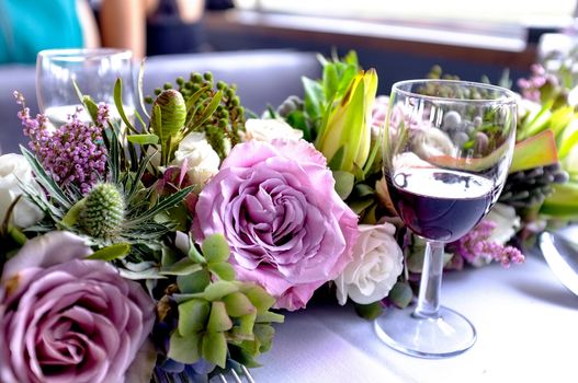 Glass of wine placed beside freshly arranged flowers on a table. Celebration time