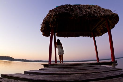 A young woman looks out over the lake at dawn