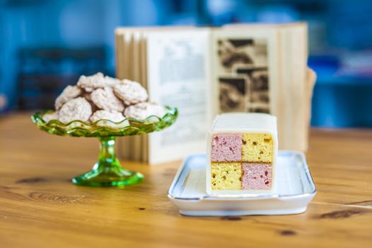 Yummy sponge cake and cookies for you. Enjoy them. Baking book in the background.