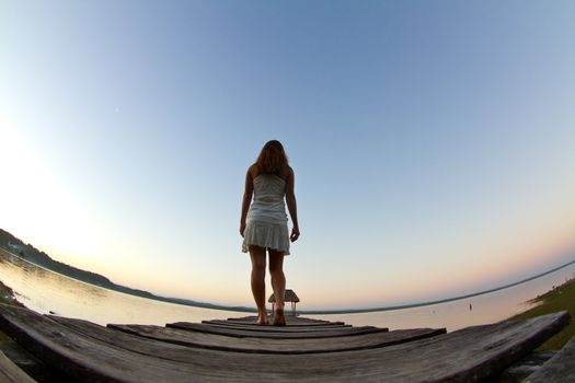 A young woman investigates the early morning lake.