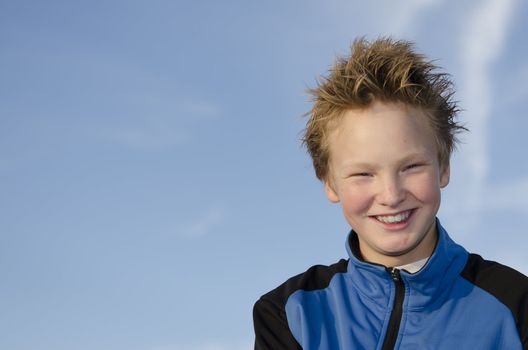 Happy teenager with spiky hair against blue sky background