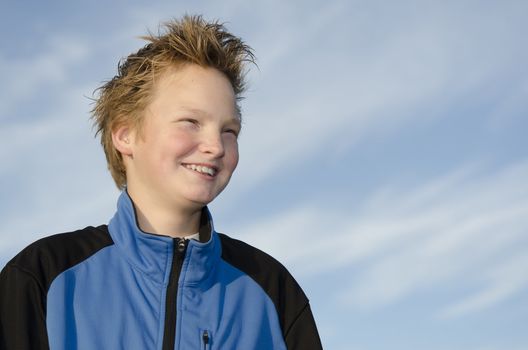 Portrait of laughing youngster against blue sky background