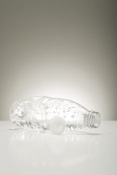 Clear plastic bottle coated in water droplets lying on its side on a studio countertop conceptual of clean pure fresh bottled water for good health