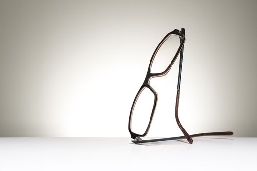 Pair of modern fashionable spectacles balanced in an upright position on a white studio background with copyspace conceptual of vision, correction, optometry and healthcare