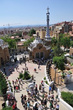 Barcelona, Spain - June 19, 2010:  visitors crowd inside entrance yard  of  Park Guell with scenic Barcelona view. Park Guell is famous creation of modernist architect Antonio Gaudi.