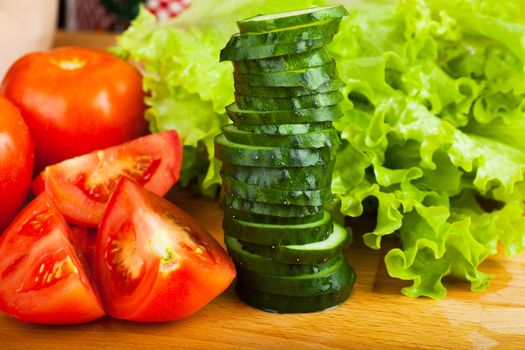 Vegetables (tomato, cucumber, salad) on a wooden table