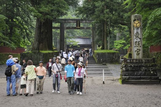 Nikko, Japan - June 22, 2008: Tourists walk at Toshogu shrine entrance by rainy summer time. Toshogu is  World Heritage site and contains five structures that are National Japanese Treasures. It is famous as a mausoleum site of Tokugawa Ieyasu, founder of the Tokugawa shogunate, which ruled Japan for over 250 years until 1868.