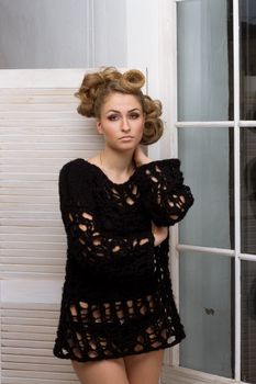 Beautiful girl with make-up and hair standing near the window