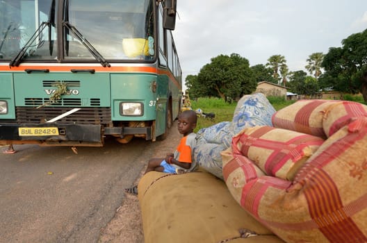 Kartiak,Senegal-September 18,2012 :An unidentified African child sitting on mattresses at the bus stop waiting to go to the ritual of Boukoutt of Initiation ceremony on September 18, 2012 in Kartiak, Senegal. The ceremony occurs every 30 years and celebrates boys becoming men.