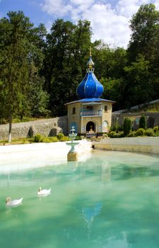 Monastery Tsyganeshty Moldova. Small church over the rill and a pool of water and white swans. 