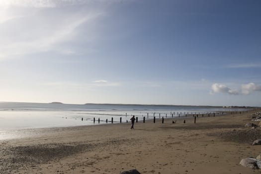 sunshine over the beach breakers in Youghal county Cork Ireland on a summers day with jogger