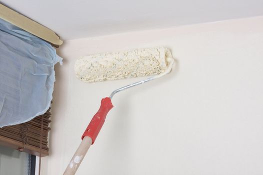 house painter using a paint roller, painting a wall in motion